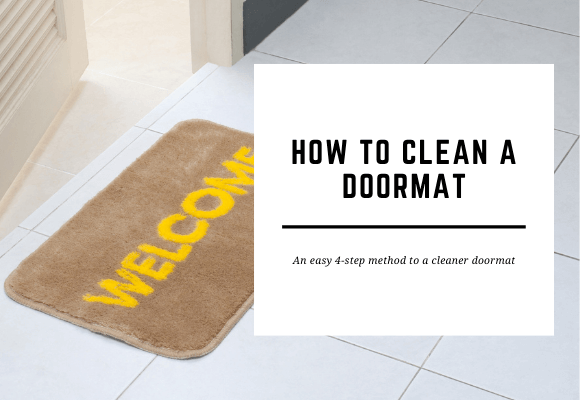 A brown door mat with the word 'Welcome' in yellow is placed in front of an ajar door. The blog title reads How to Clean a Doormat.