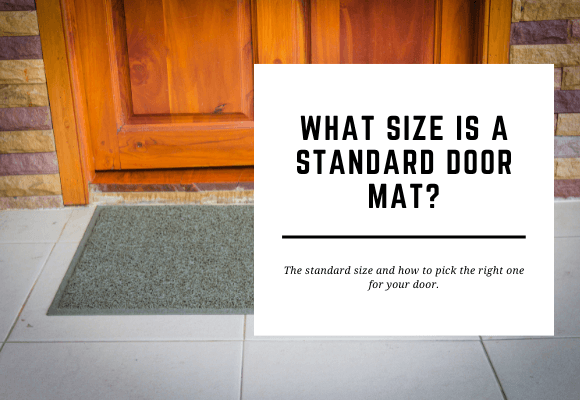 A grey door mat is placed outside a large wooden door. The blog header reads What Size is a Standard Door Mat?