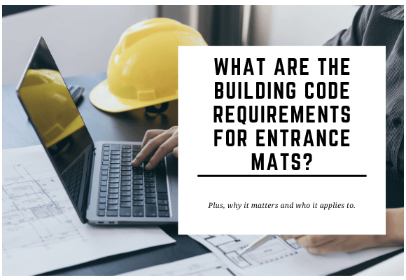 A yellow hard hat and a laptop are placed on a desk where someone is working. The blog header reads What are The Building Code Requirements for Entrance Mats?